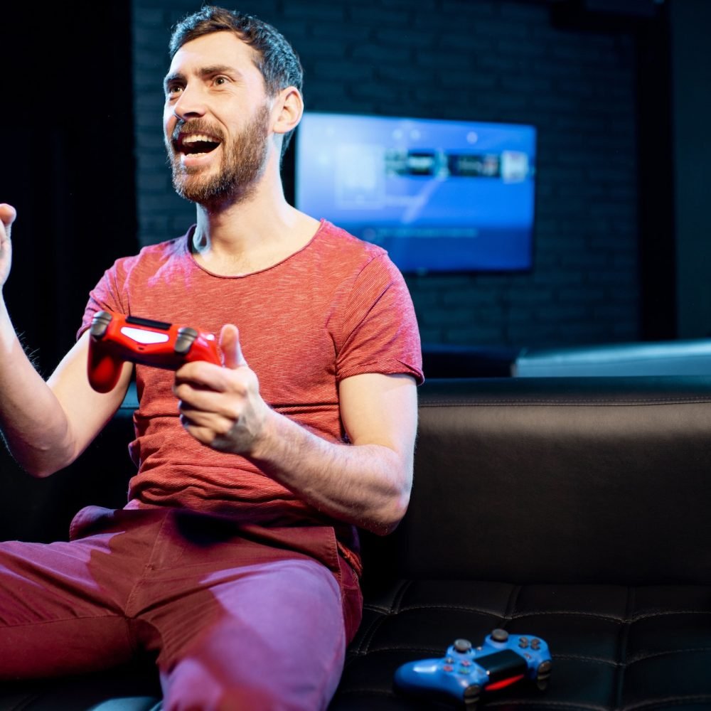 Happy man playing video games with gaming console in the club